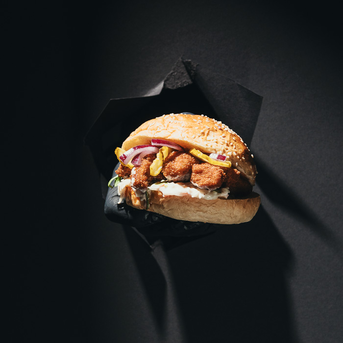 Burger mit knusprigen Hähnchenstücken, roten Zwiebeln und Peperoni