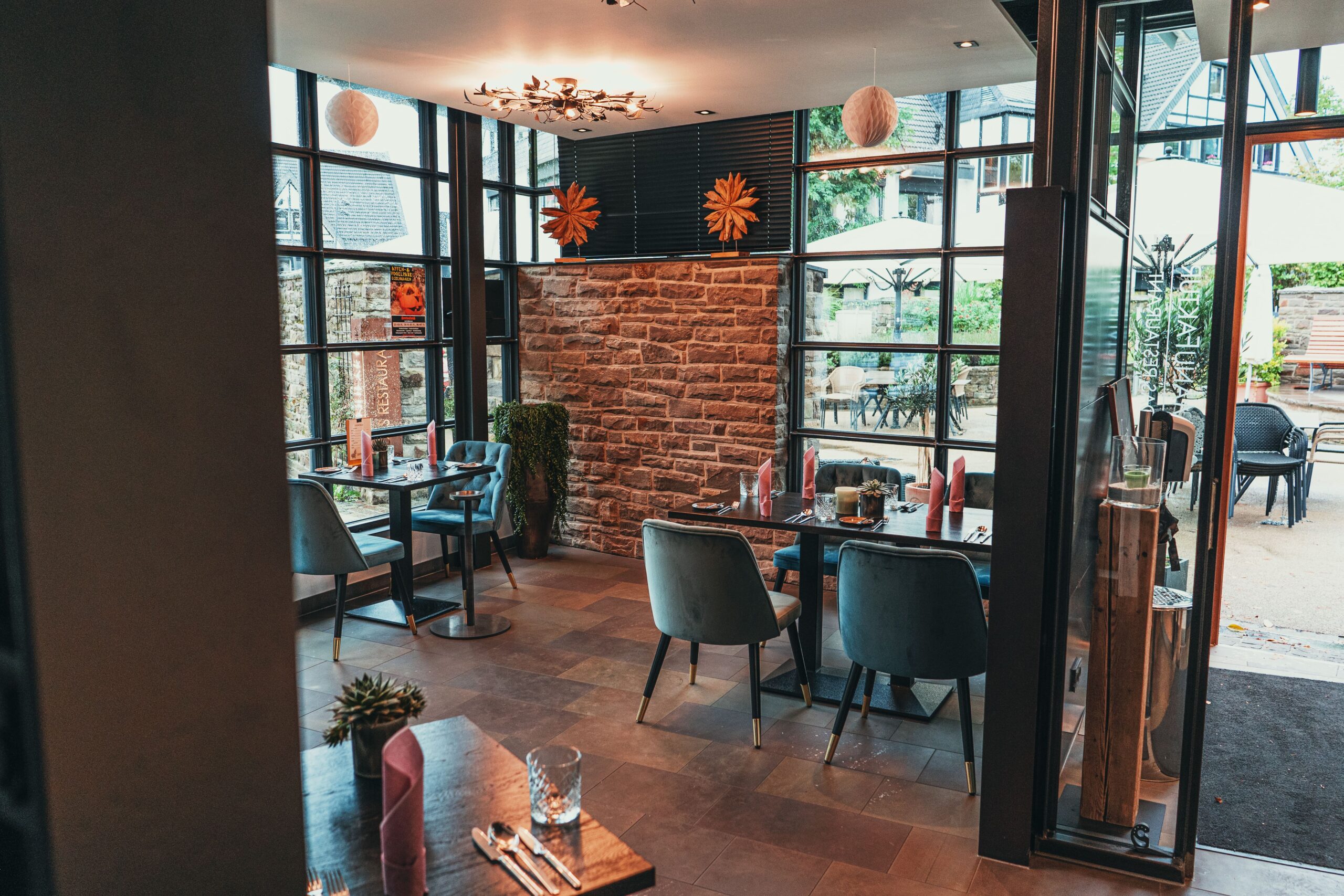 Wintergarten des Restaurants mit Natursteinwand, Samtstühlen und Blick auf die Terrasse
