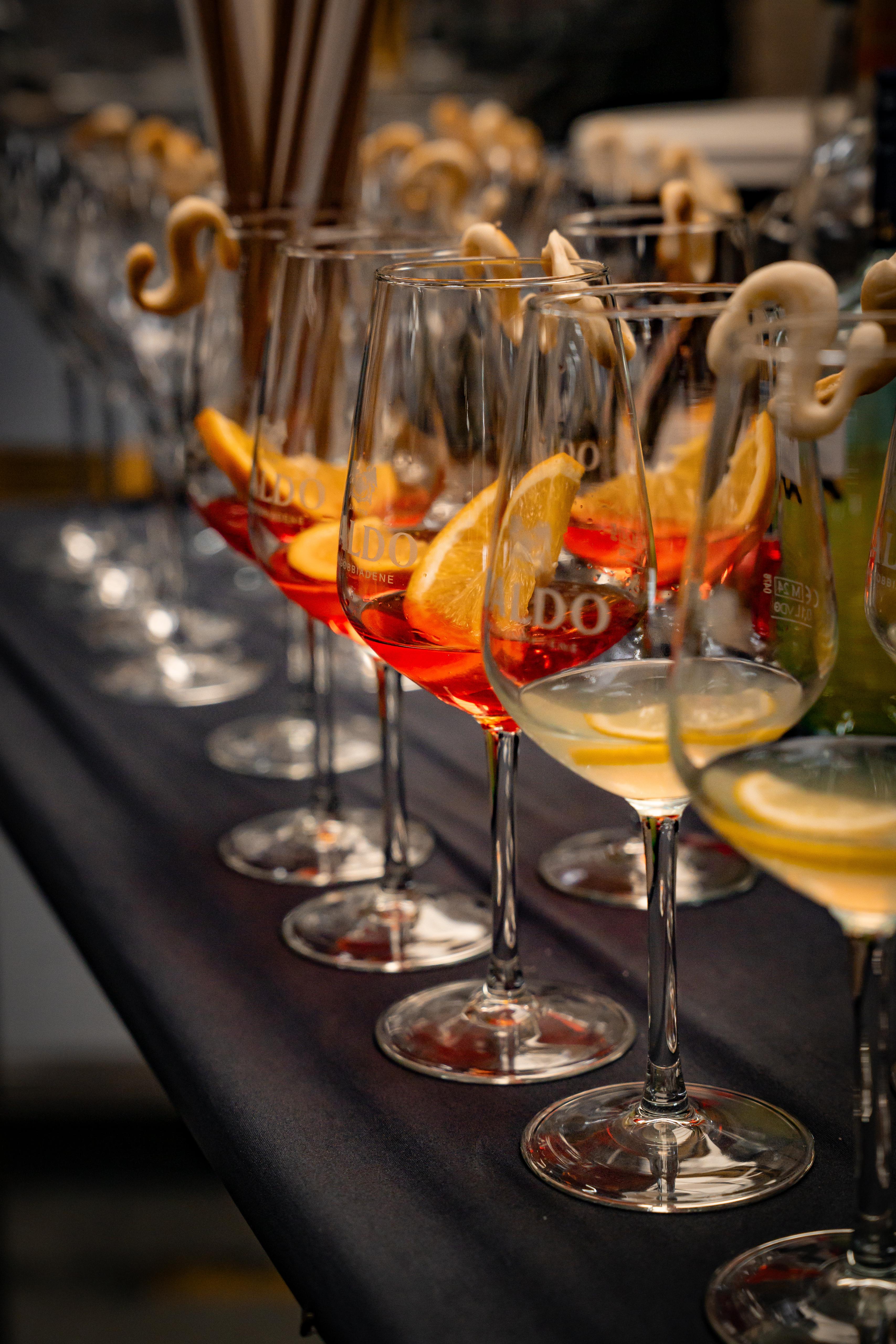 Weingläser mit Aperitif-Spritz und Zitronenscheiben auf einer Theke