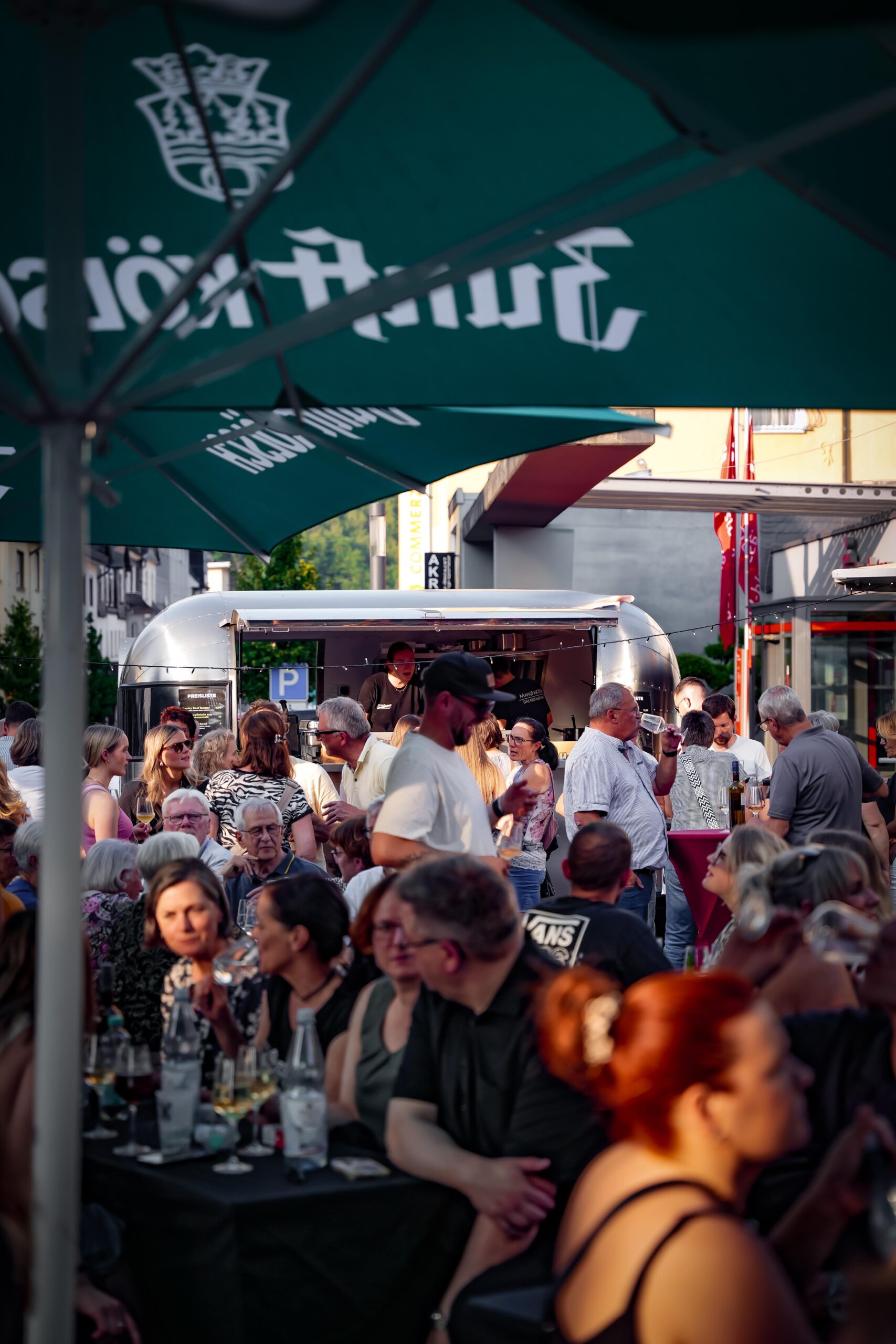Voll besetzte Tische unter Zunft-Kölsch-Schirmen, im Hintergrund der Airstream-Foodtruck
