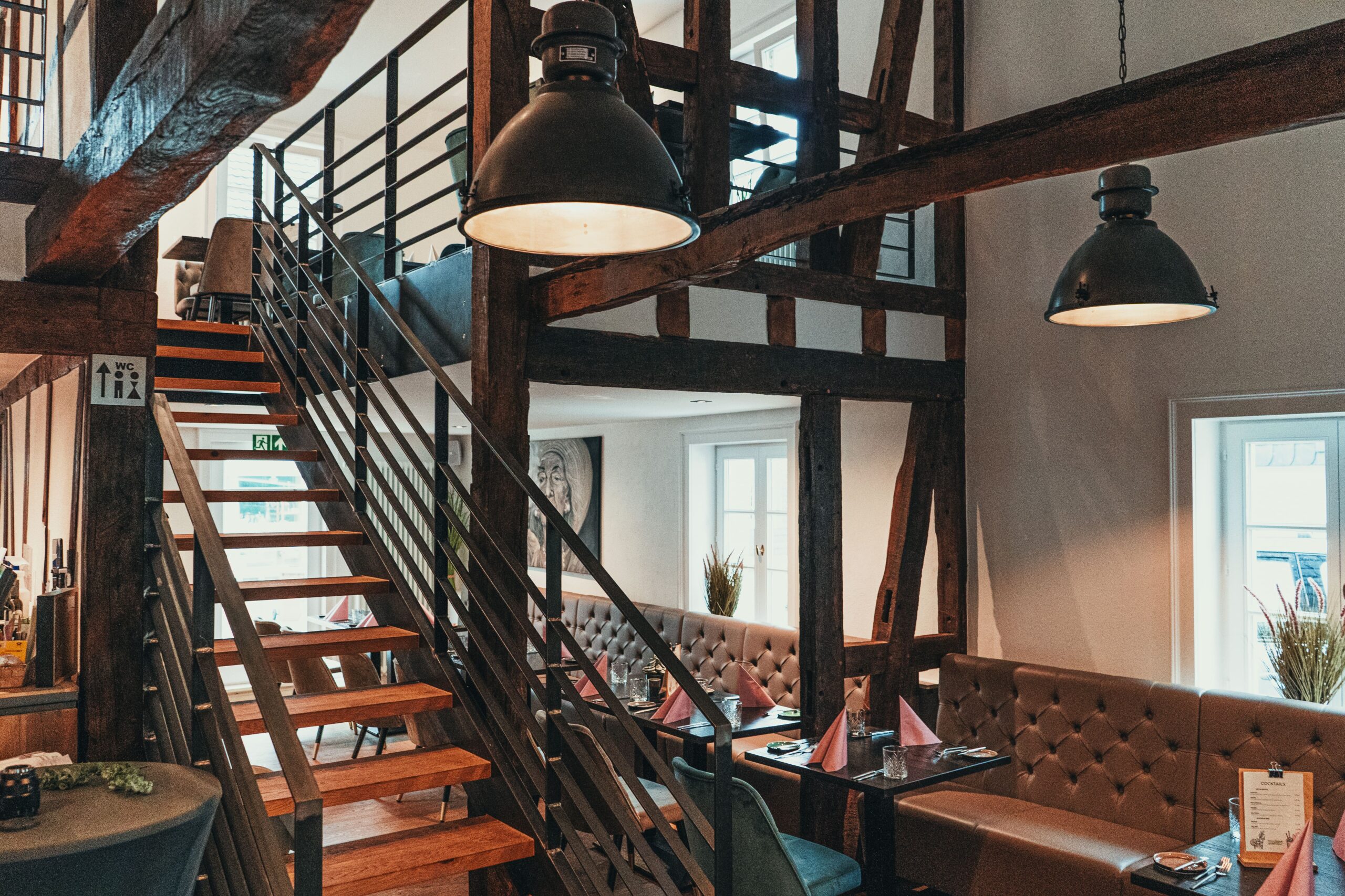 Restaurant ManuFaktur: Fachwerkraum mit Treppe zur Galerie, Polsterbänken und Pendelleuchten