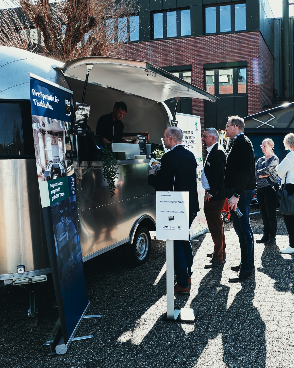 Geschäftsgäste am Foodtruck bei der Hausmesse von Soennecken, daneben Roll-up-Banner